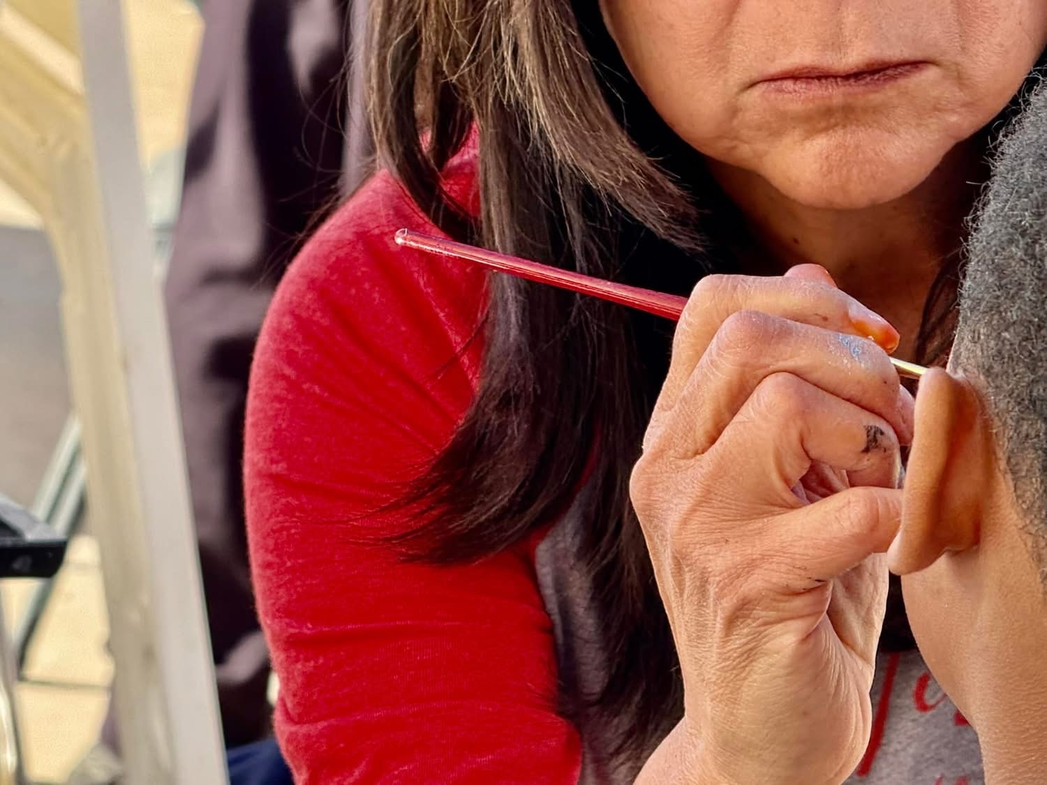 Volunteer painting a child's face at A Day of Giving 2025
