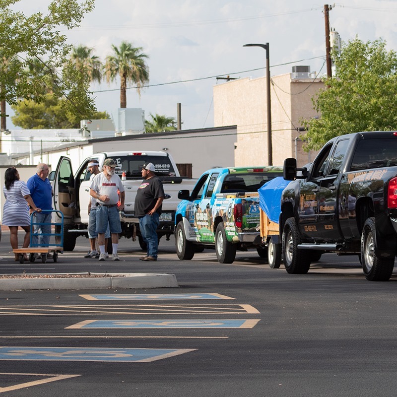 Trucks from local trades and AE Outdoor Living parked together unloading donations at the community center