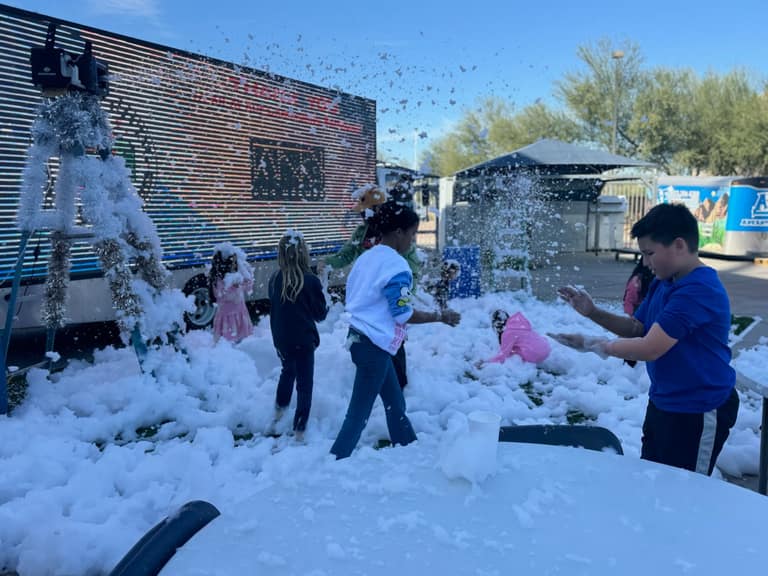 Kids tossing snow in the air at the snow-play area during A Day of Giving 2025