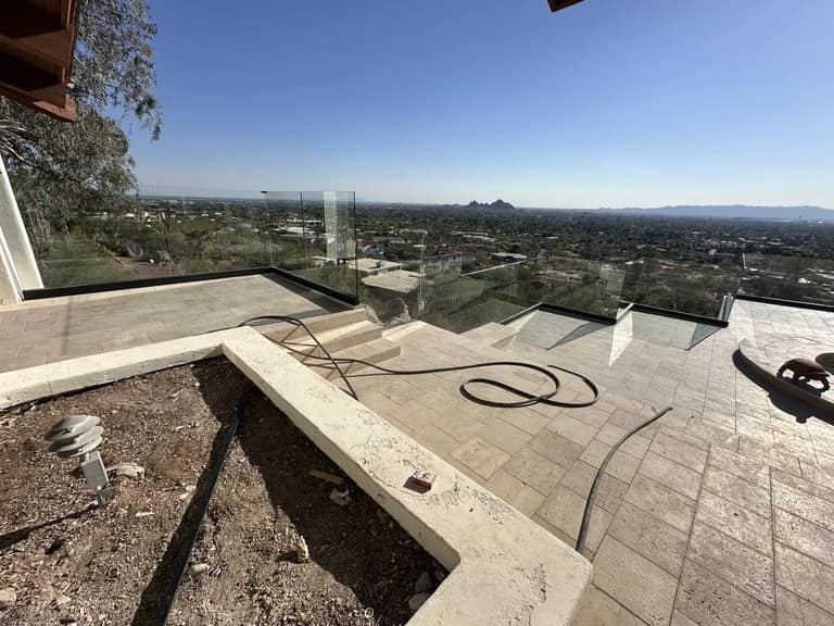 Wide view of a tiled hillside terrace with glass railing overlooking Phoenix.