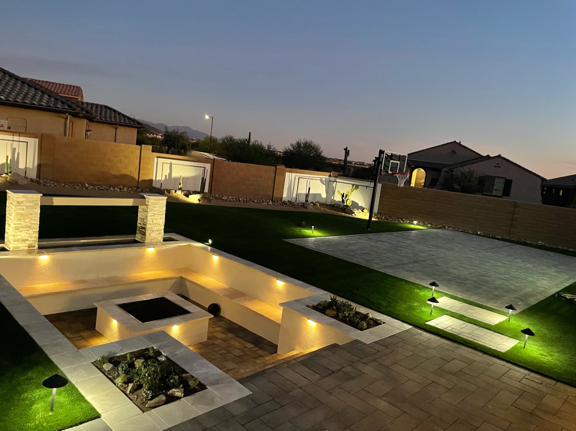 Goodyear backyard paver sport court, artificial turf lawn and sunken firepit lounge with mountain sunset view