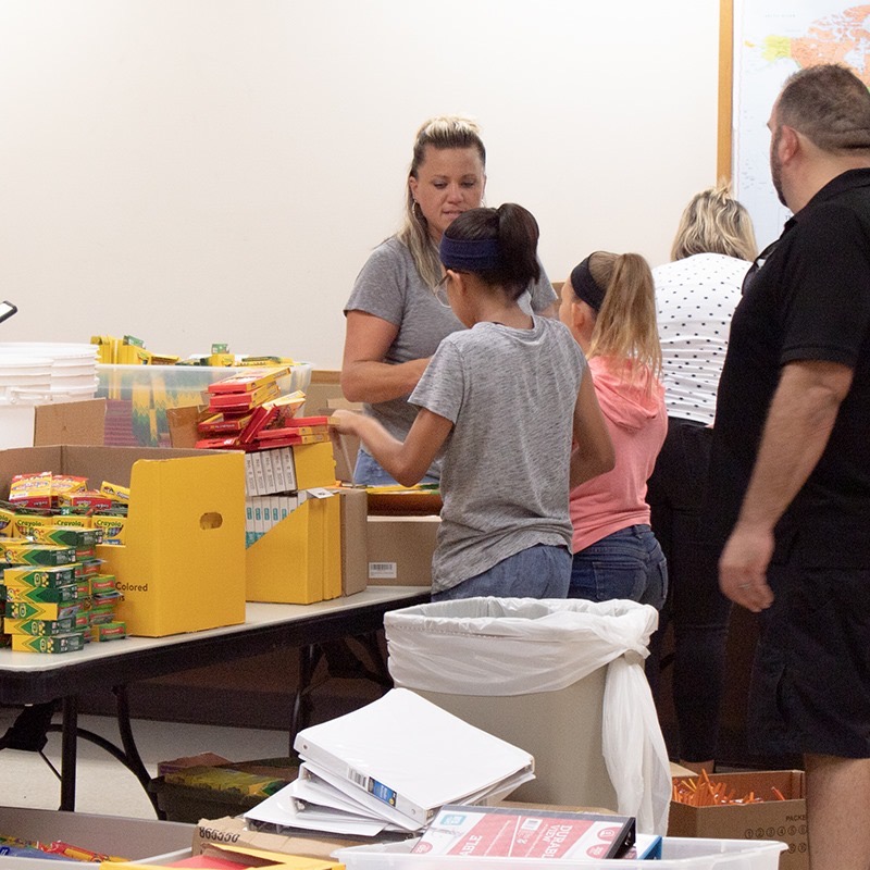 Volunteers and kids sorting boxes of Crayola crayons and colored pencils on a folding table