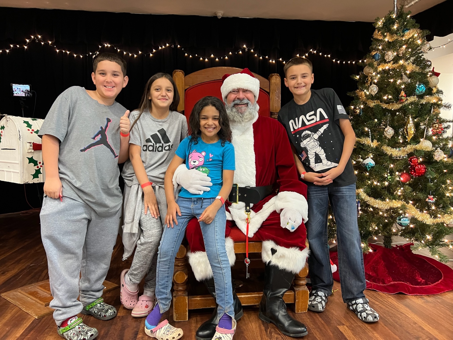 Four siblings gathered with Santa for a group photo at Shop With a Cop