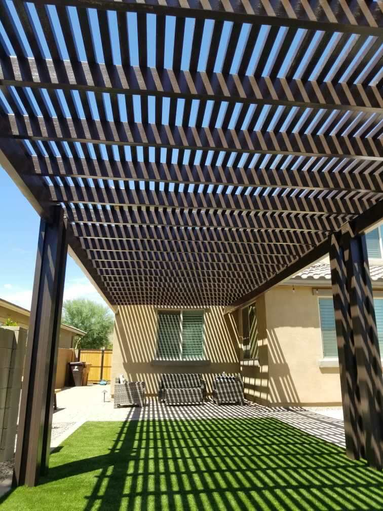 The Meadows (Peoria) freestanding bronze alumawood lattice pergola casting shade over artificial turf lawn and rear paver patio by AE Outdoor Living