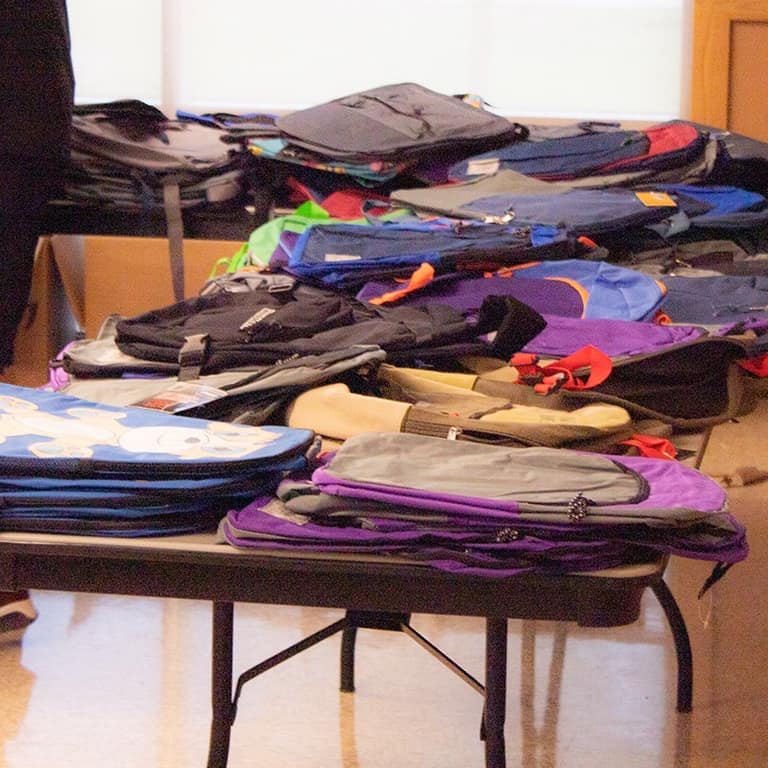 Rows of backpacks spread across tables before distribution at the backpack drive