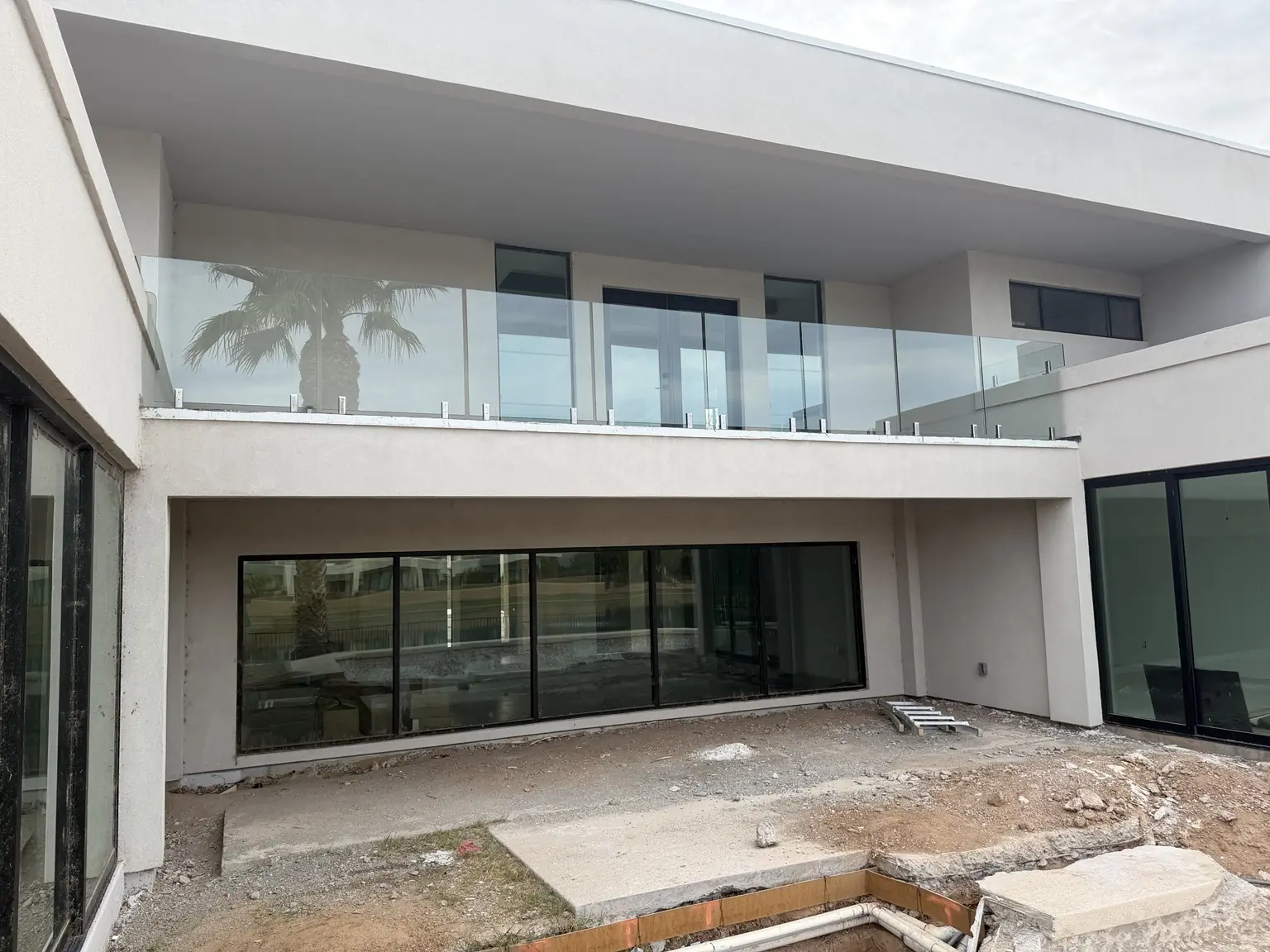 Wide glass railing spanning the upper balcony of a modern Scottsdale home during construction.