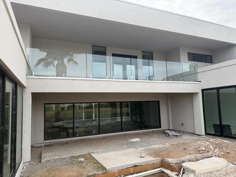 Wide glass railing spanning the upper balcony of a modern Scottsdale home during construction.