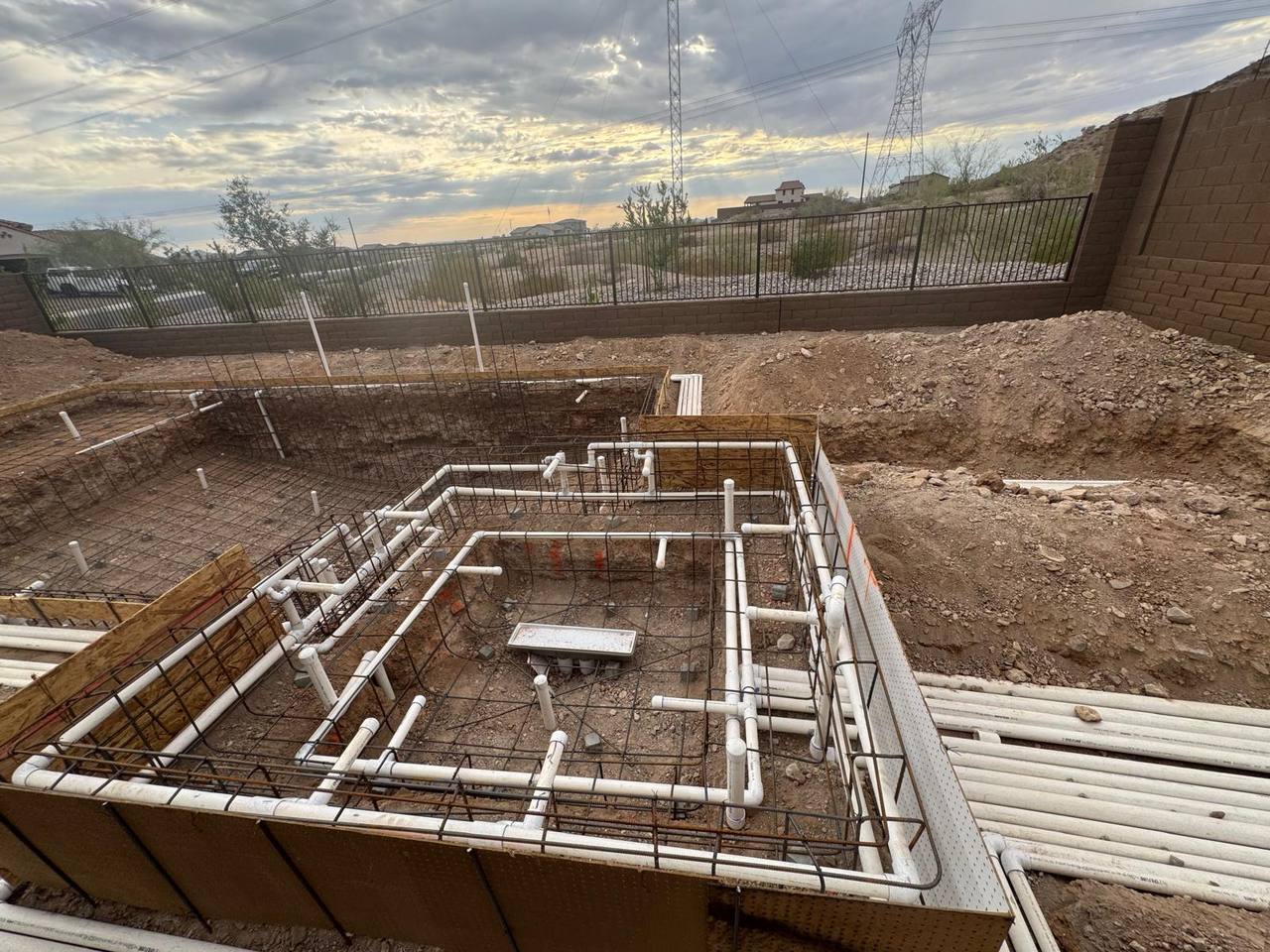 Pool and raised spa shell pre-gunite at dusk — separated suction/return and dedicated spa plumbing visible.