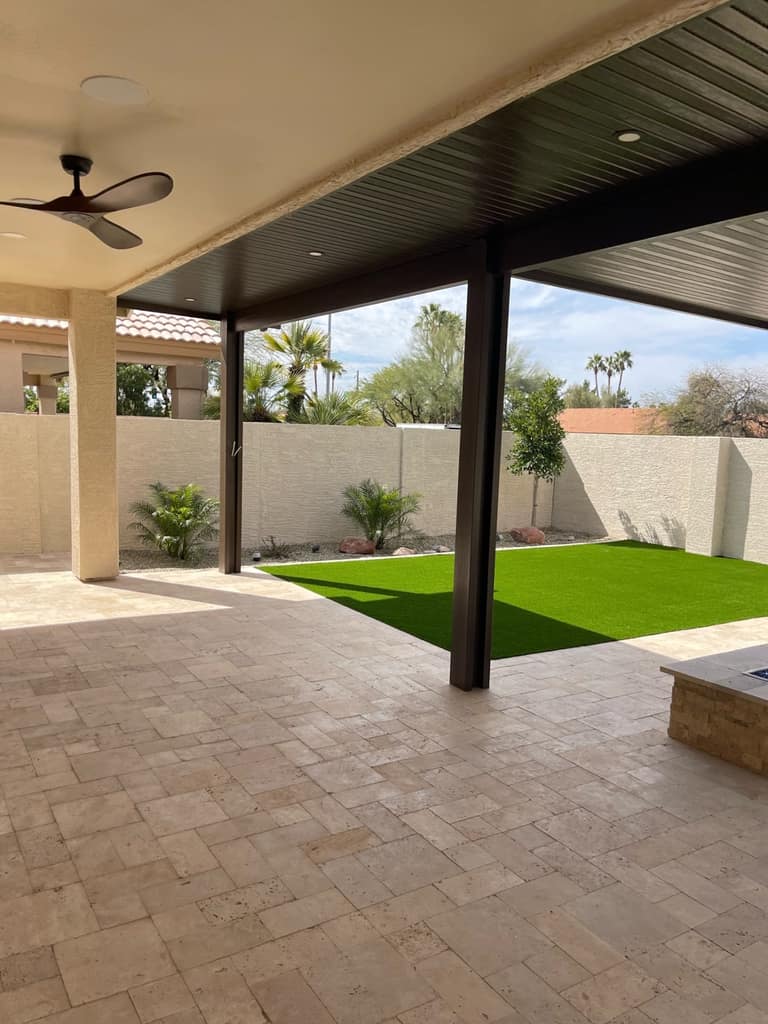 Covered patio extension with integrated fans, lighting, and a clean turf lawn beyond.