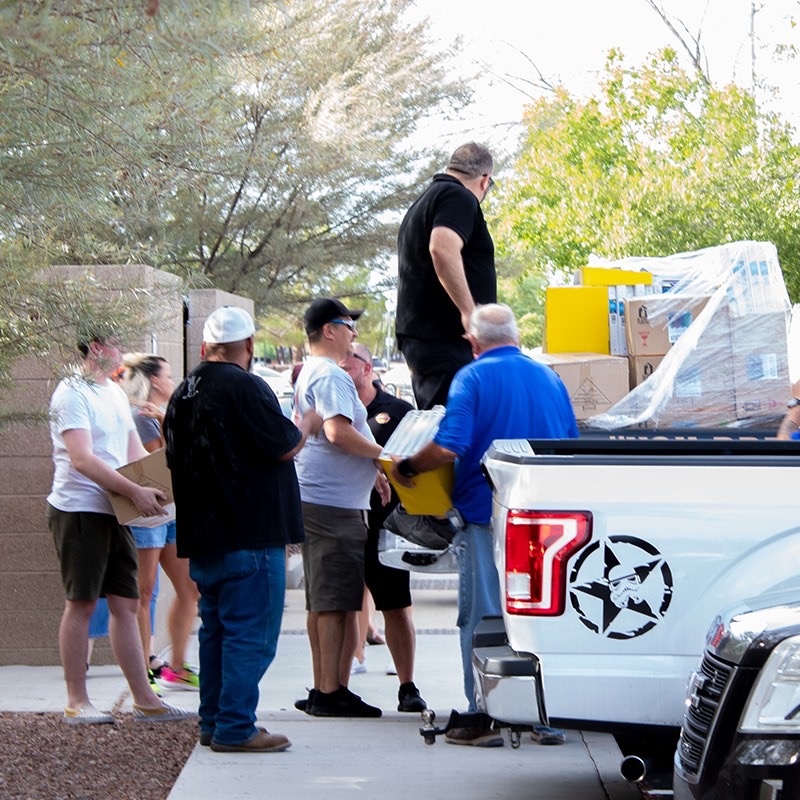 Volunteers forming a line passing boxes of supplies from a pickup truck into the community center