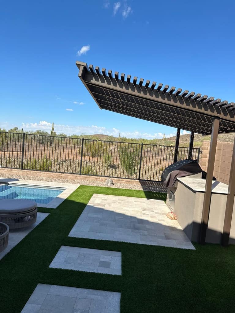 Louvered shade system above the outdoor kitchen, viewed from the pool and spa side.