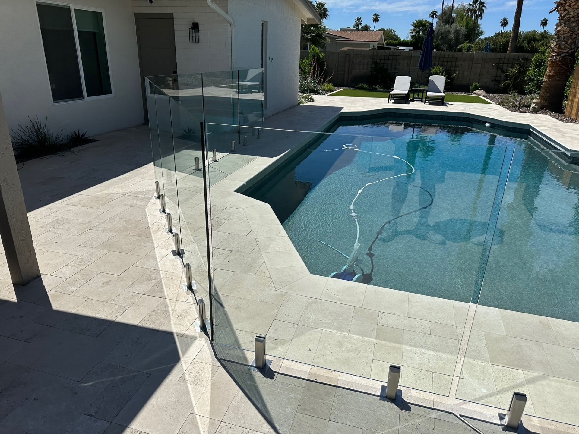 Frameless Sonoran Glass & Fence pool fencing around a travertine pool deck