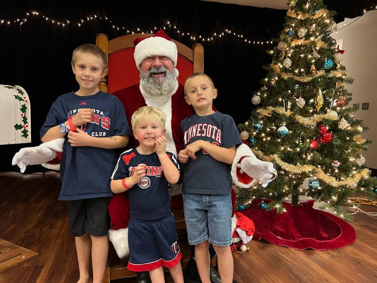 Three young brothers in Minnesota Twins shirts with Santa at Shop With a Cop