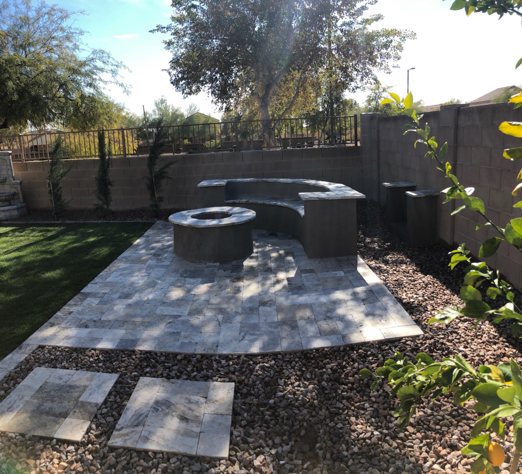 Verrado travertine paver patio with curved seat wall, gas fire pit, and turf edge