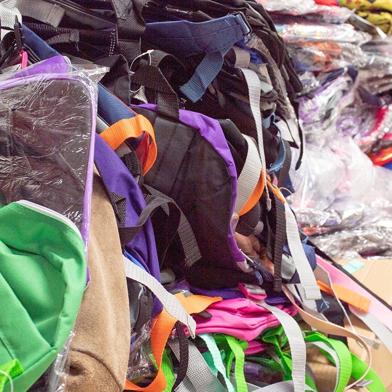 Pile of brand-new backpacks in plastic wrap stacked together before the drive