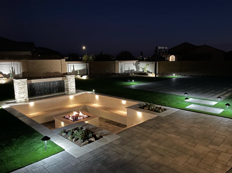 Goodyear paver patio and sunken firepit lounge under sheer-descent water feature with turf and paver sport court beyond