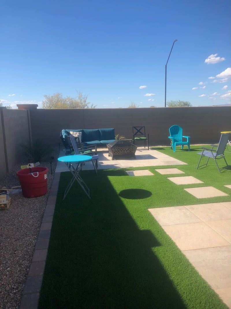 Buckeye paver patio with fire pit and artificial turf lawn framed by paver ribbon