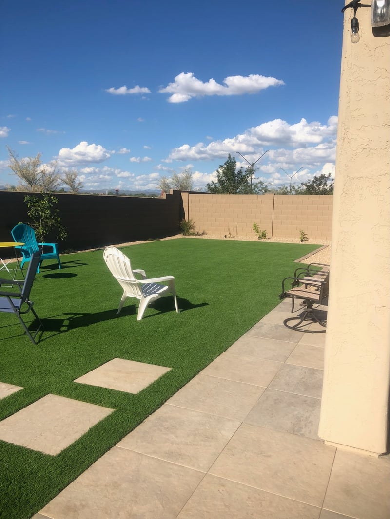 Buckeye backyard artificial turf lawn with travertine paver patio and stepping-stone ribbon by AE Outdoor Living
