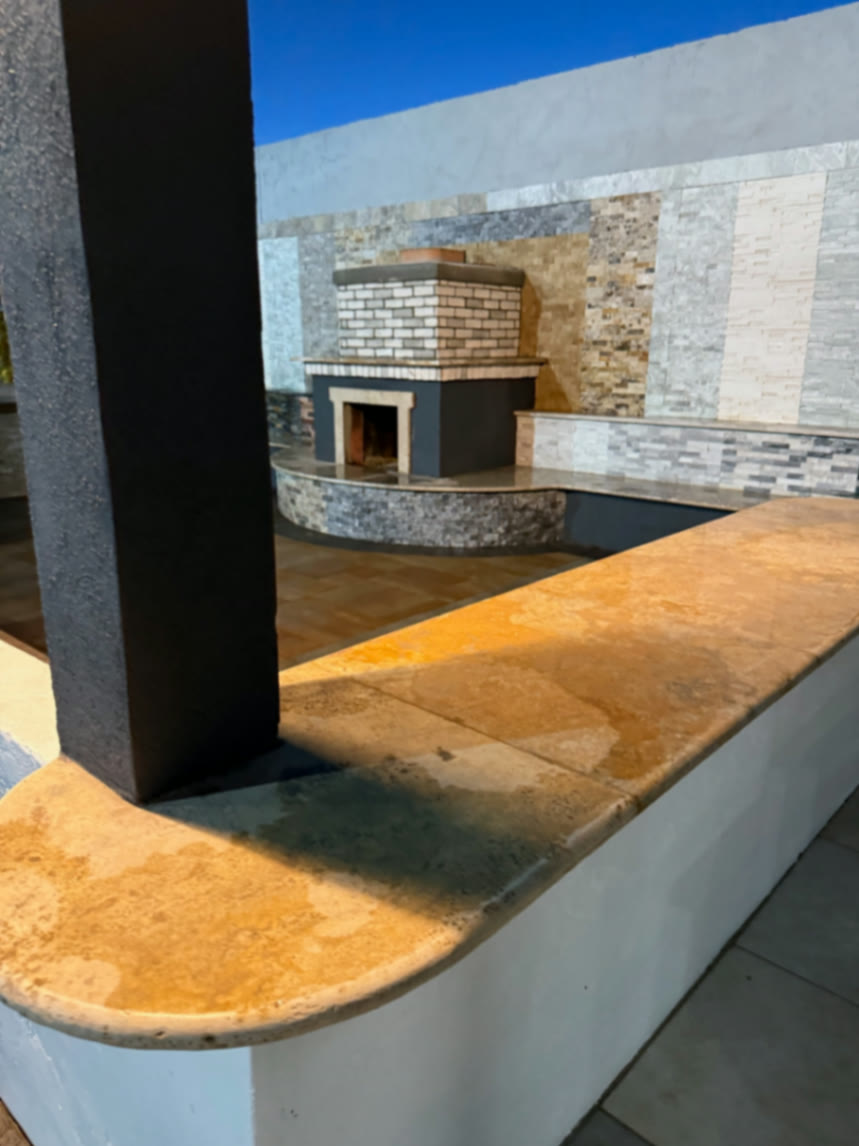 Close-up of curved bench coping leading to a masonry fireplace and mixed-stone finish wall