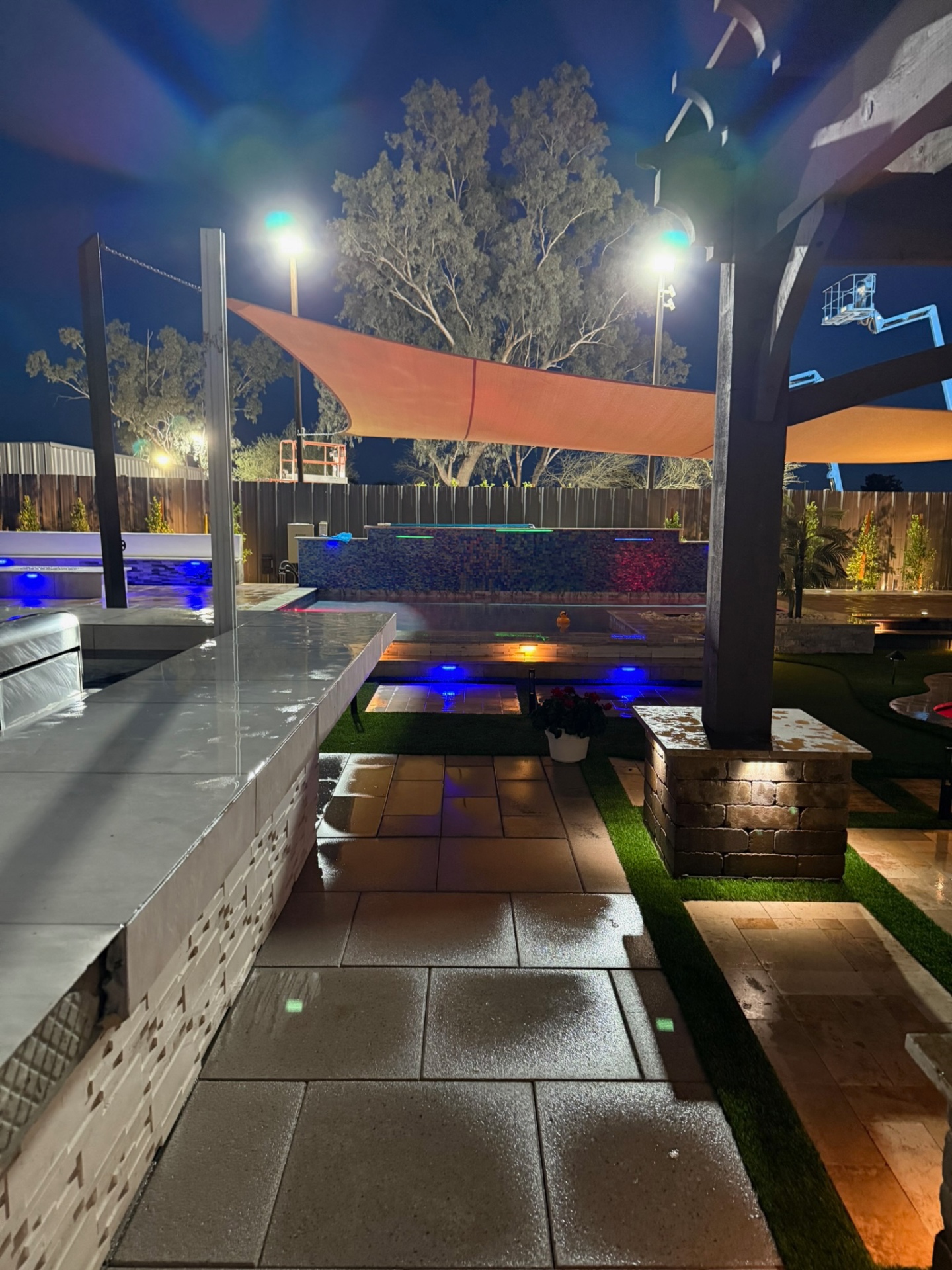 Lit paver patio under sail shades with pergola post detail