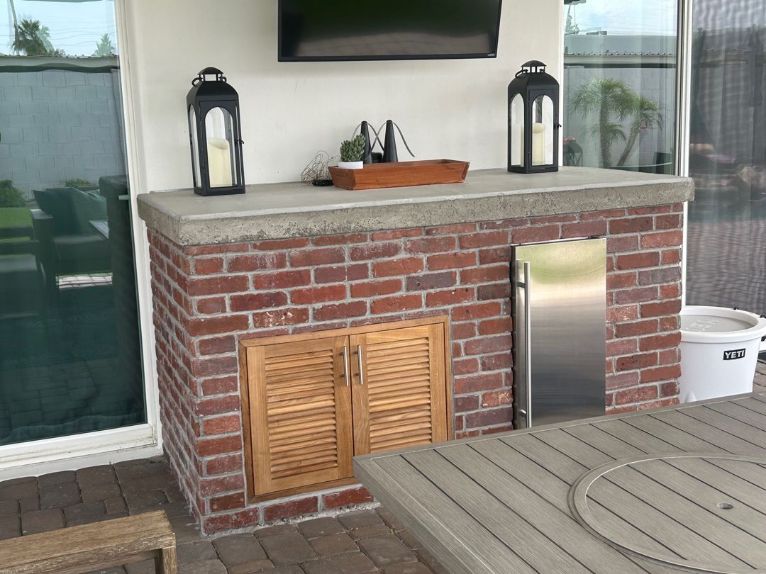Built-in outdoor kitchen with BBQ island, stone veneer, counter, storage, and low-voltage lighting