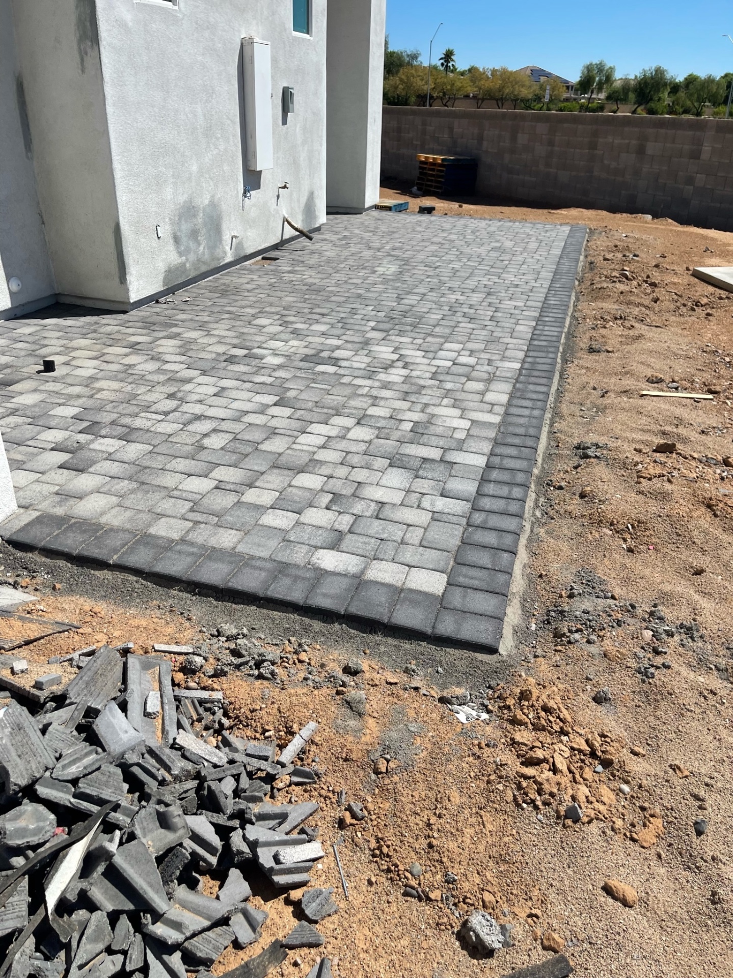 Waddell (Surprise-area) tumbled two-tone paver patio with charcoal soldier-course border set against the block wall on the 12,000 sq ft project by AE Outdoor Living