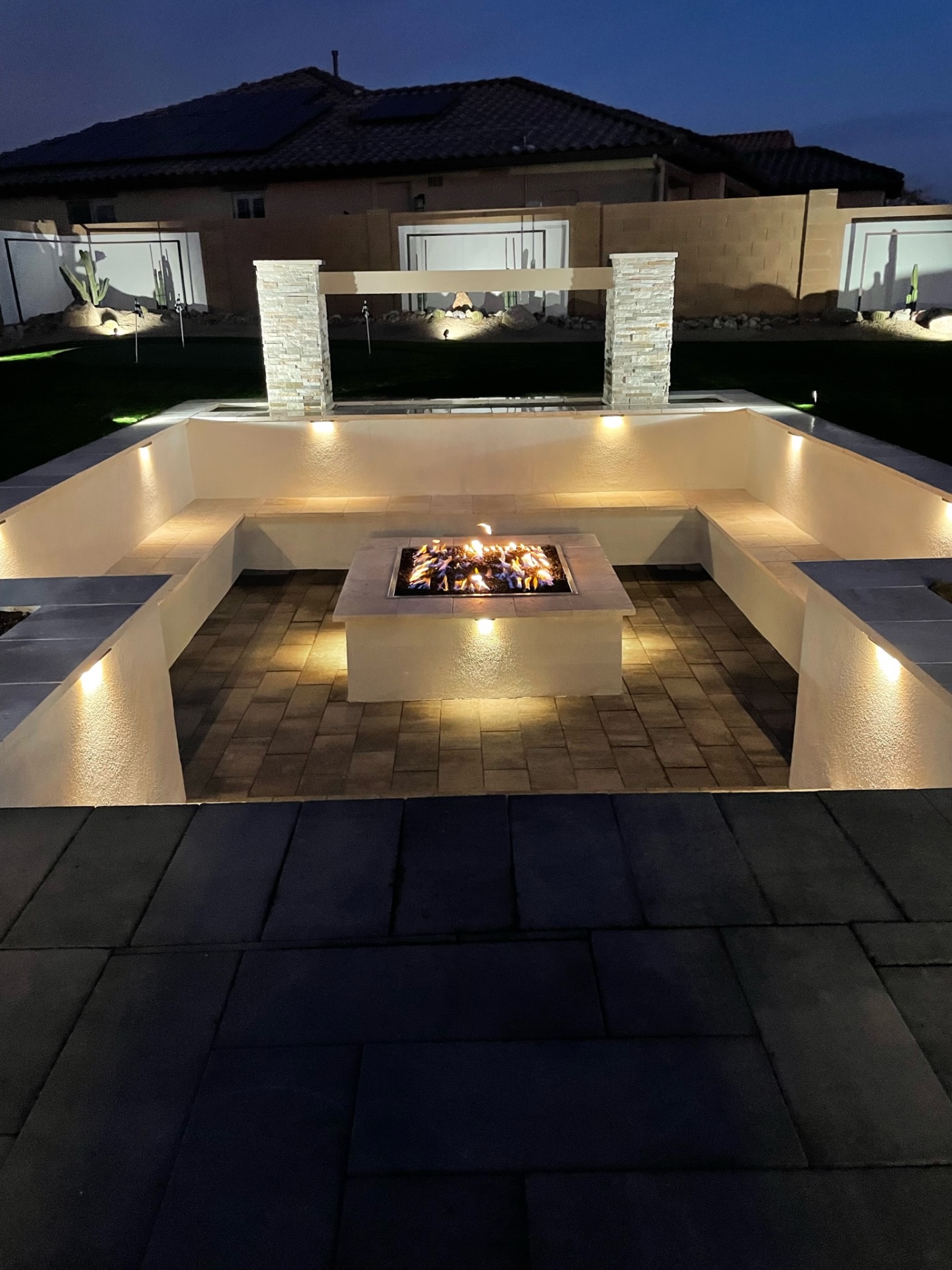 Goodyear paver firepit conversation pit with travertine benches, stacked-stone columns and sheer-descent waterwall