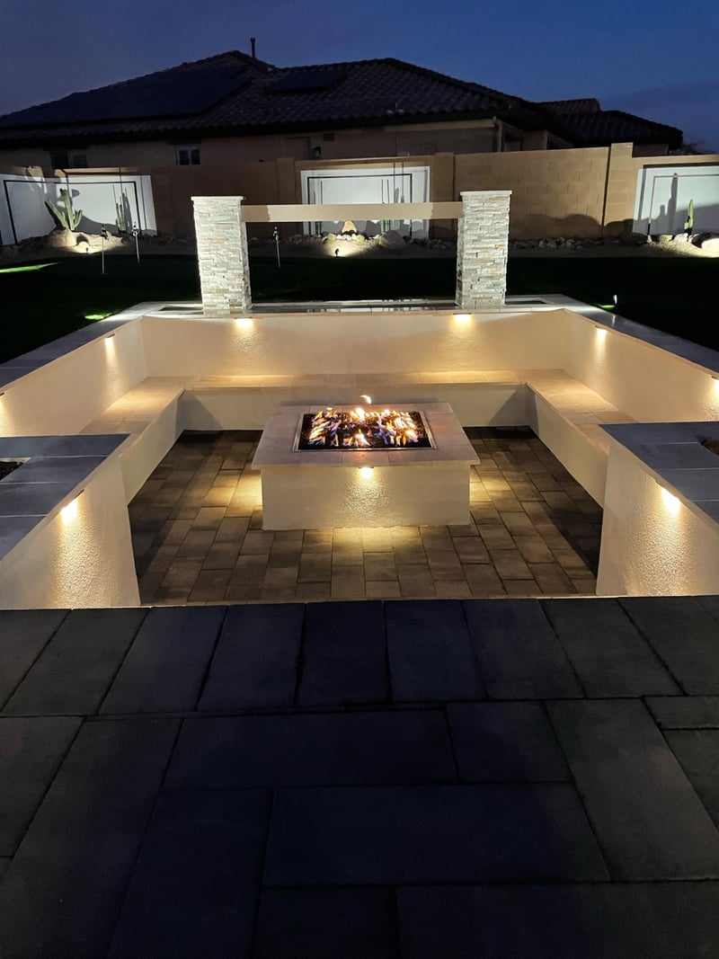 Goodyear paver firepit conversation pit with travertine benches, stacked-stone columns and sheer-descent waterwall