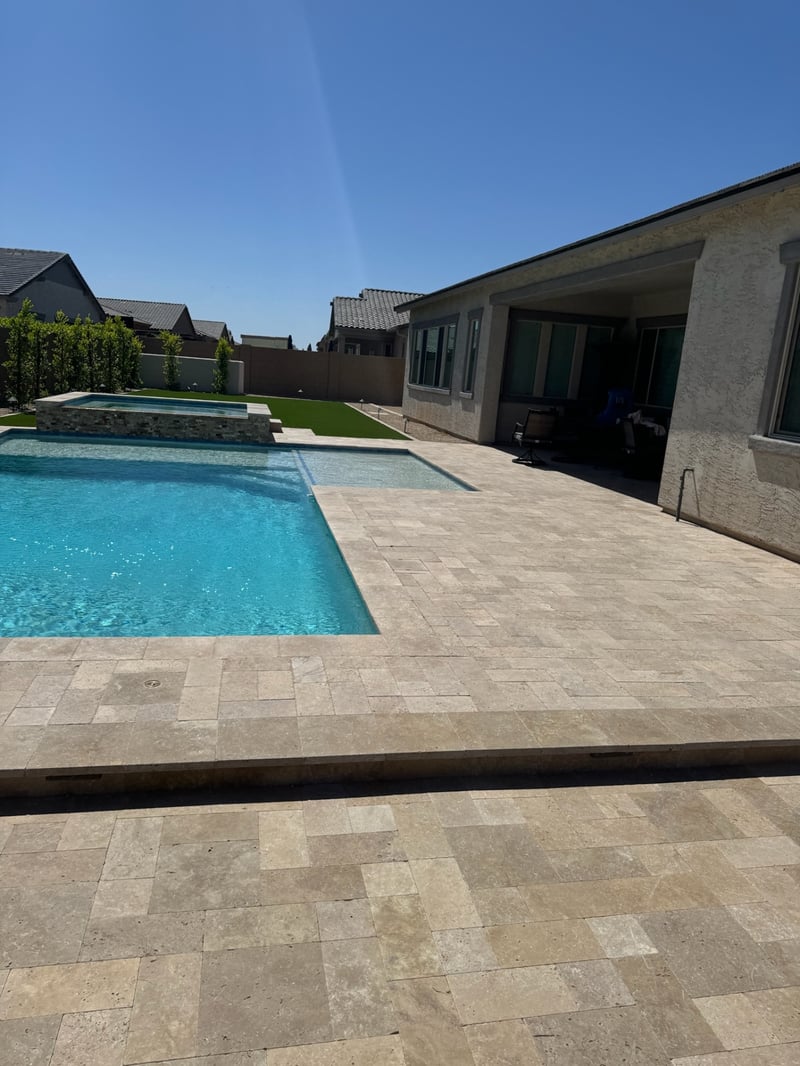 Peoria custom pool with raised spa, stacked-stone veneer, and full travertine paver pool deck