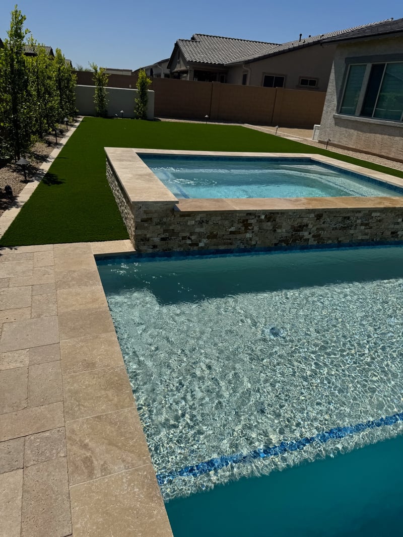 Peoria pool and raised spa with travertine coping, stacked stone spa wall, and turf side yard
