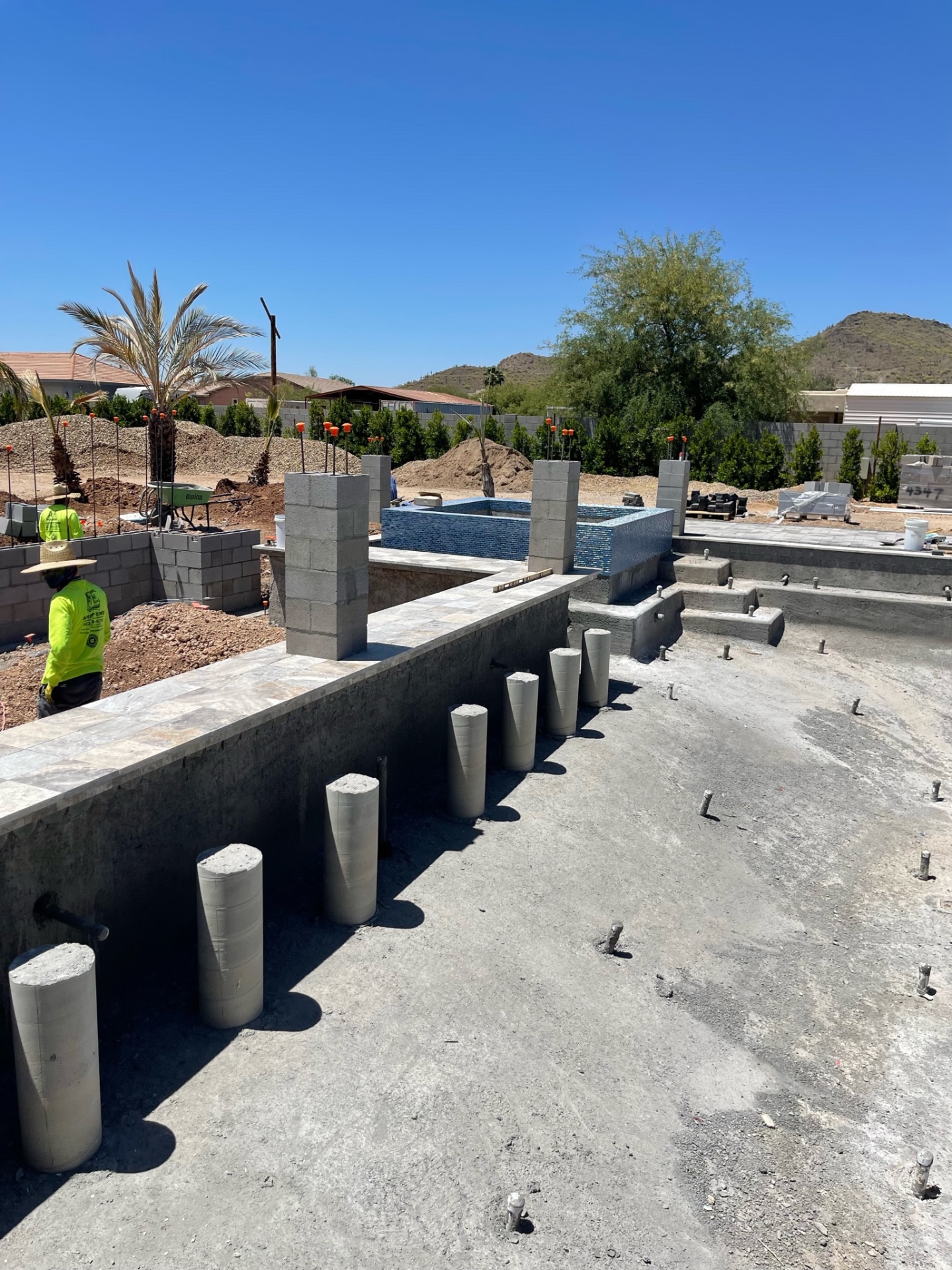 Wide view across the shell toward the raised tiled spa and block piers before final decking is completed