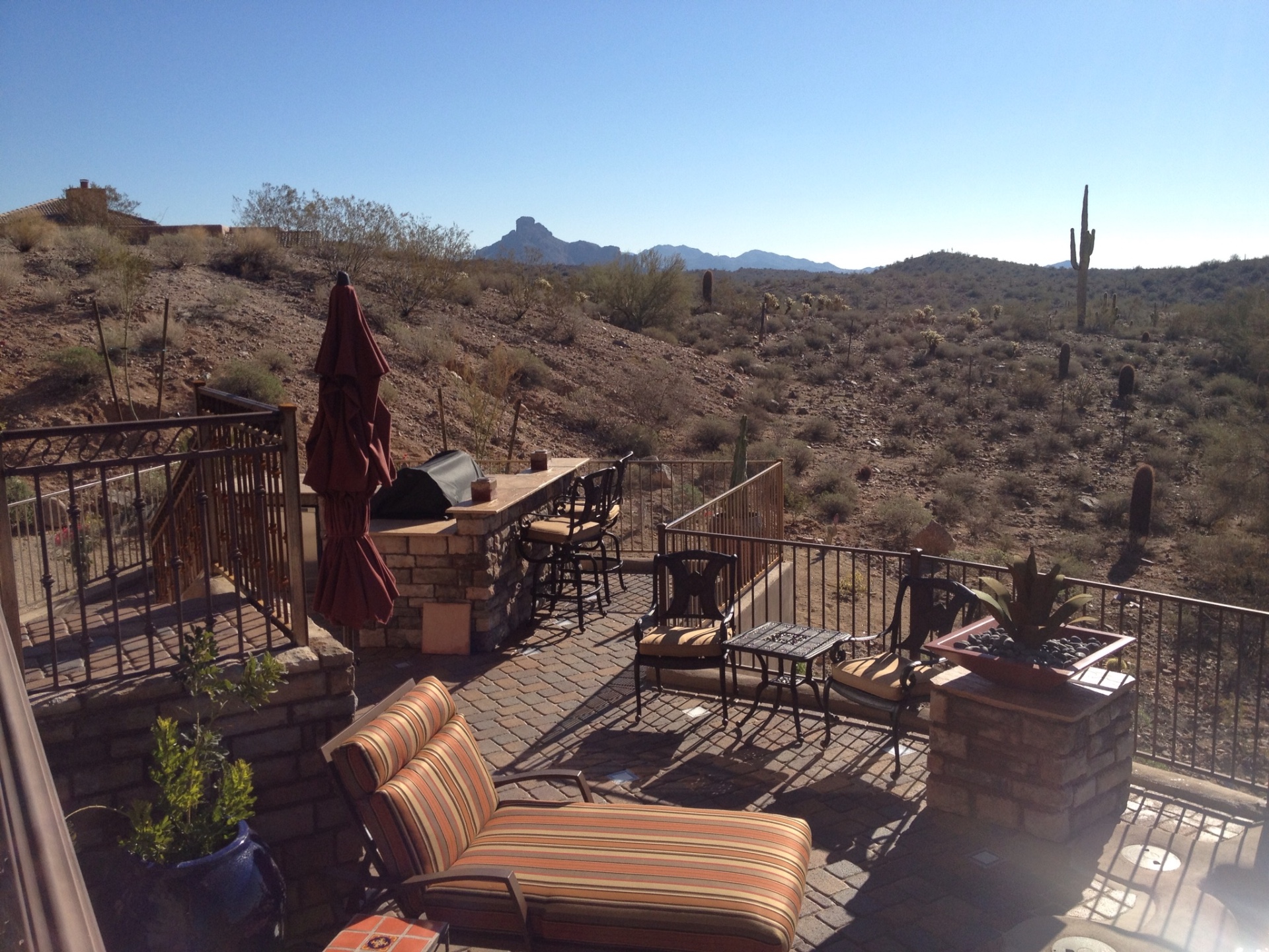 Fountain Hills paver terrace lounge with stacked-stone BBQ bar island and iron railing overlooking Sonoran Desert and saguaros