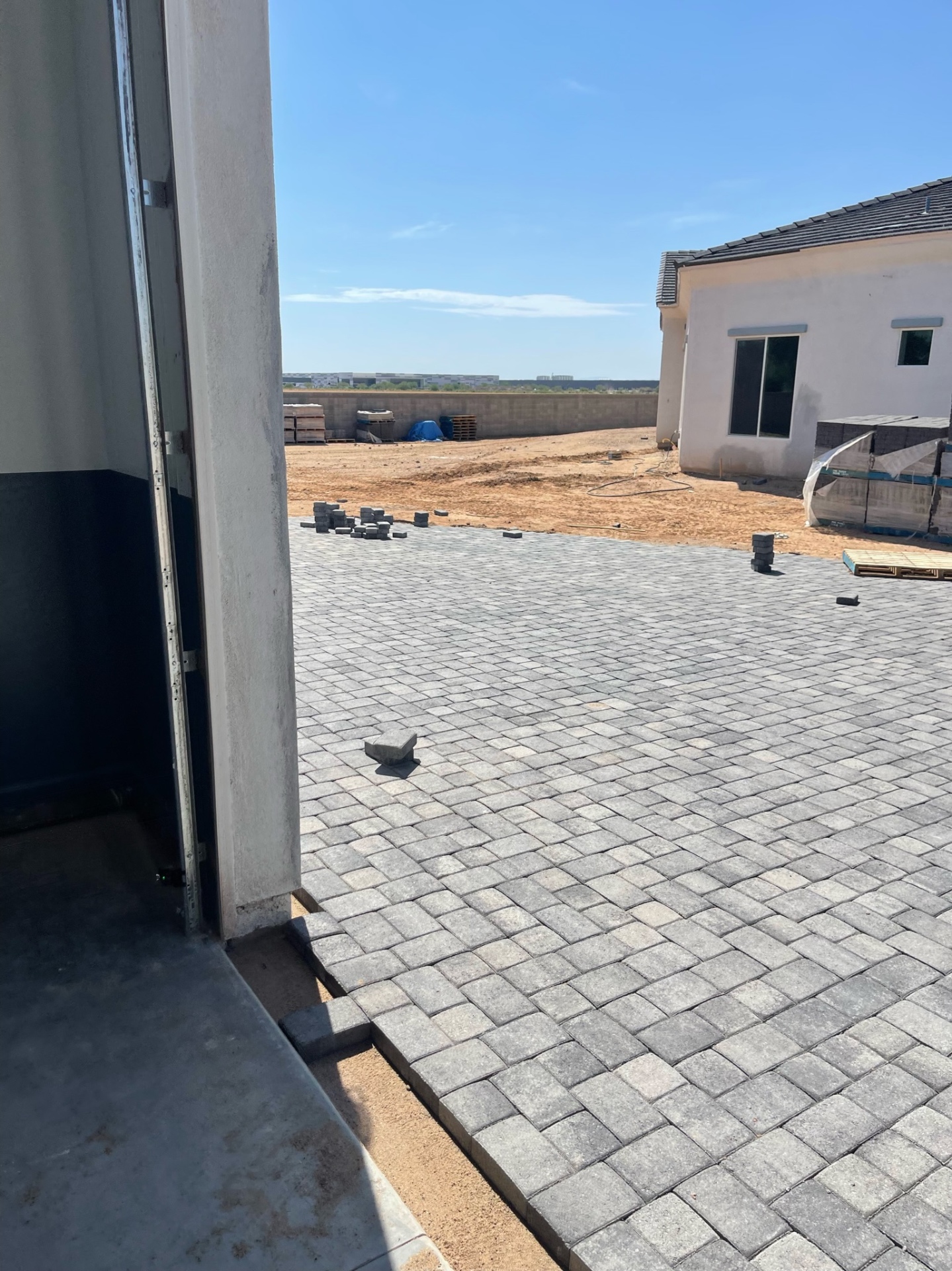 Waddell (Surprise-area) broad backyard charcoal paver field viewed from the RV garage threshold, showing a continuous patio layout across the rear yard by AE Outdoor Living