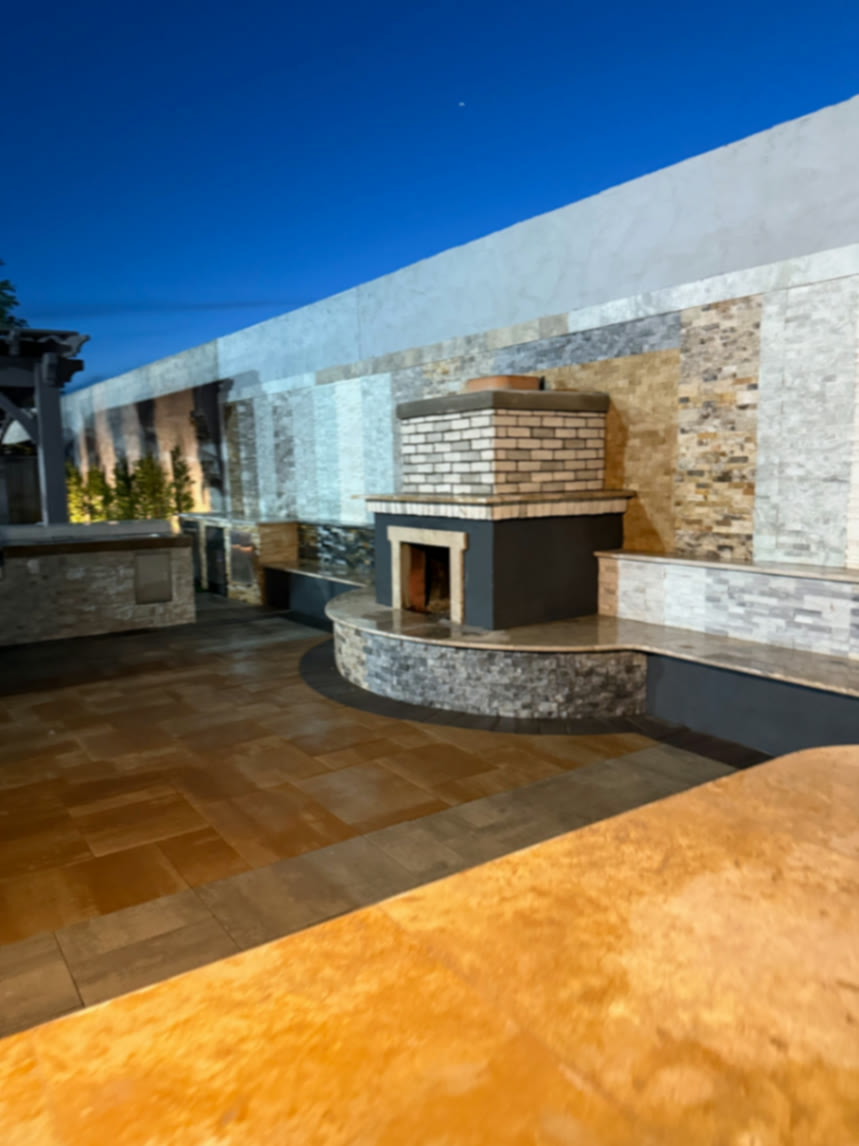 Curved fireplace and bench set against a tall mixed-stone feature wall in the showroom yard