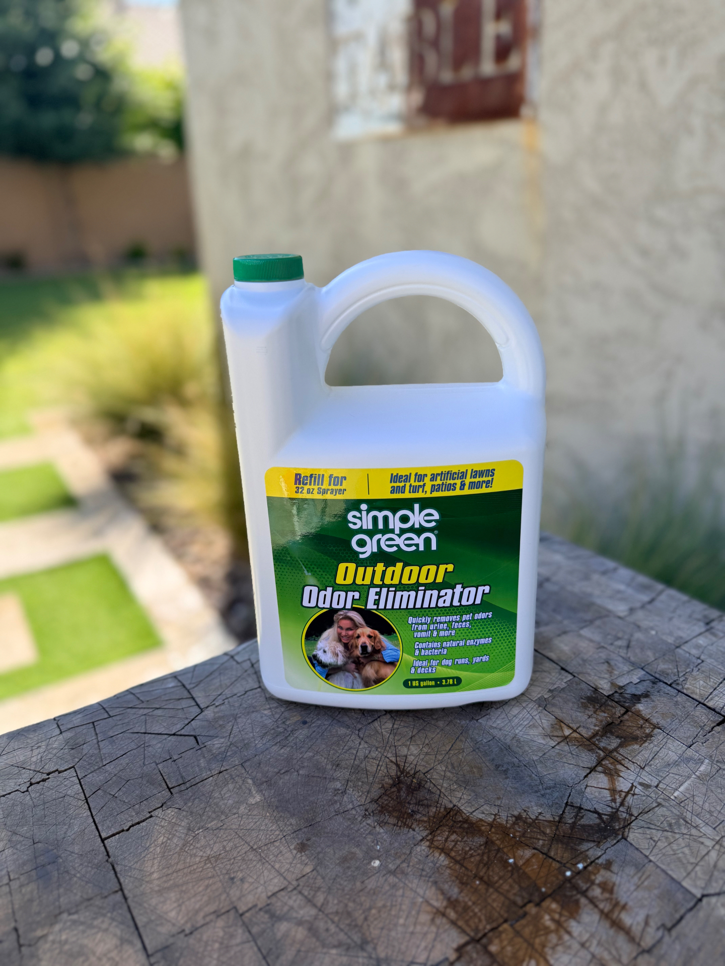 Simple Green Outdoor Odor Eliminator gallon jug on a stump table with artificial turf in the background