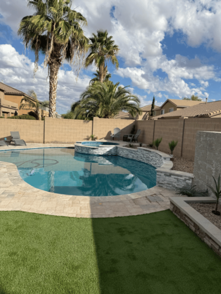 Freeform pool and raised spa with turf edge, block planters, and light travertine decking.