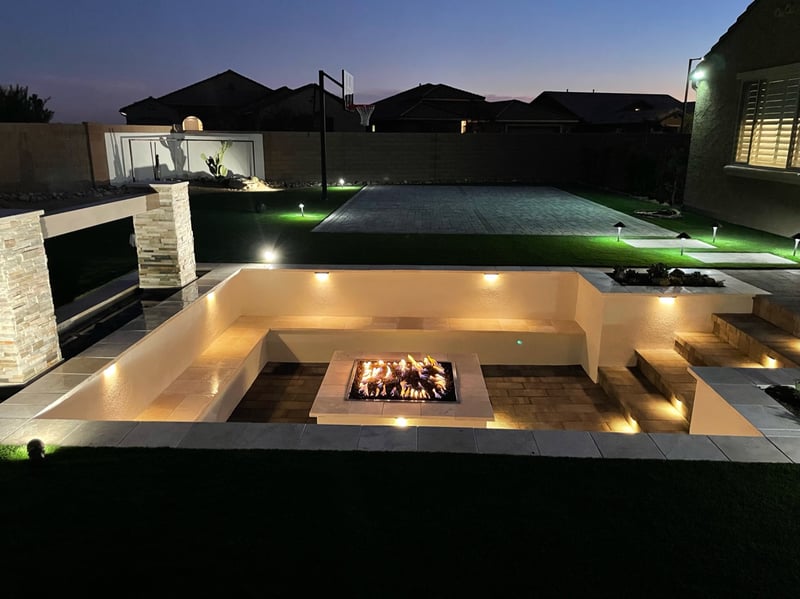 Goodyear sunken paver firepit conversation pit with travertine benches, stacked-stone water feature and paver sport court