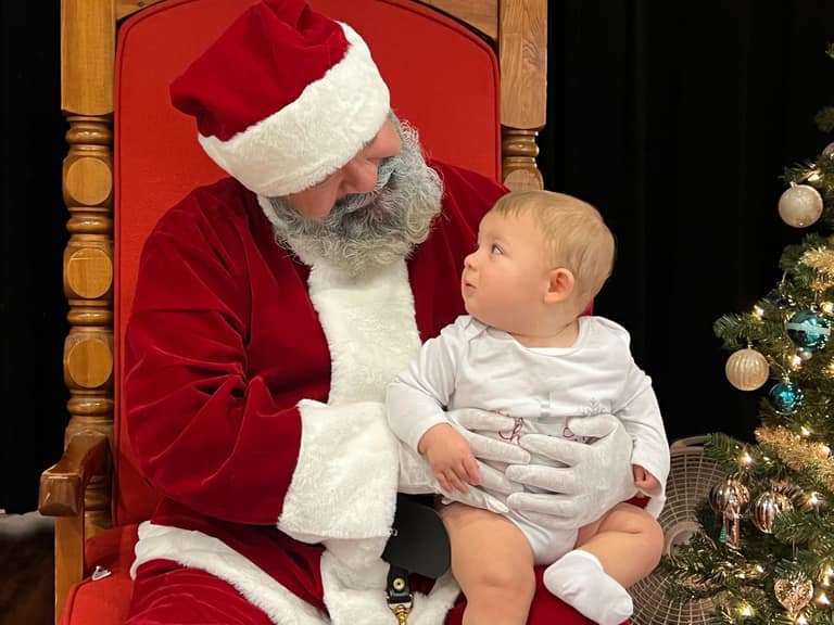 Santa holding a baby for a family photo at Shop With a Cop