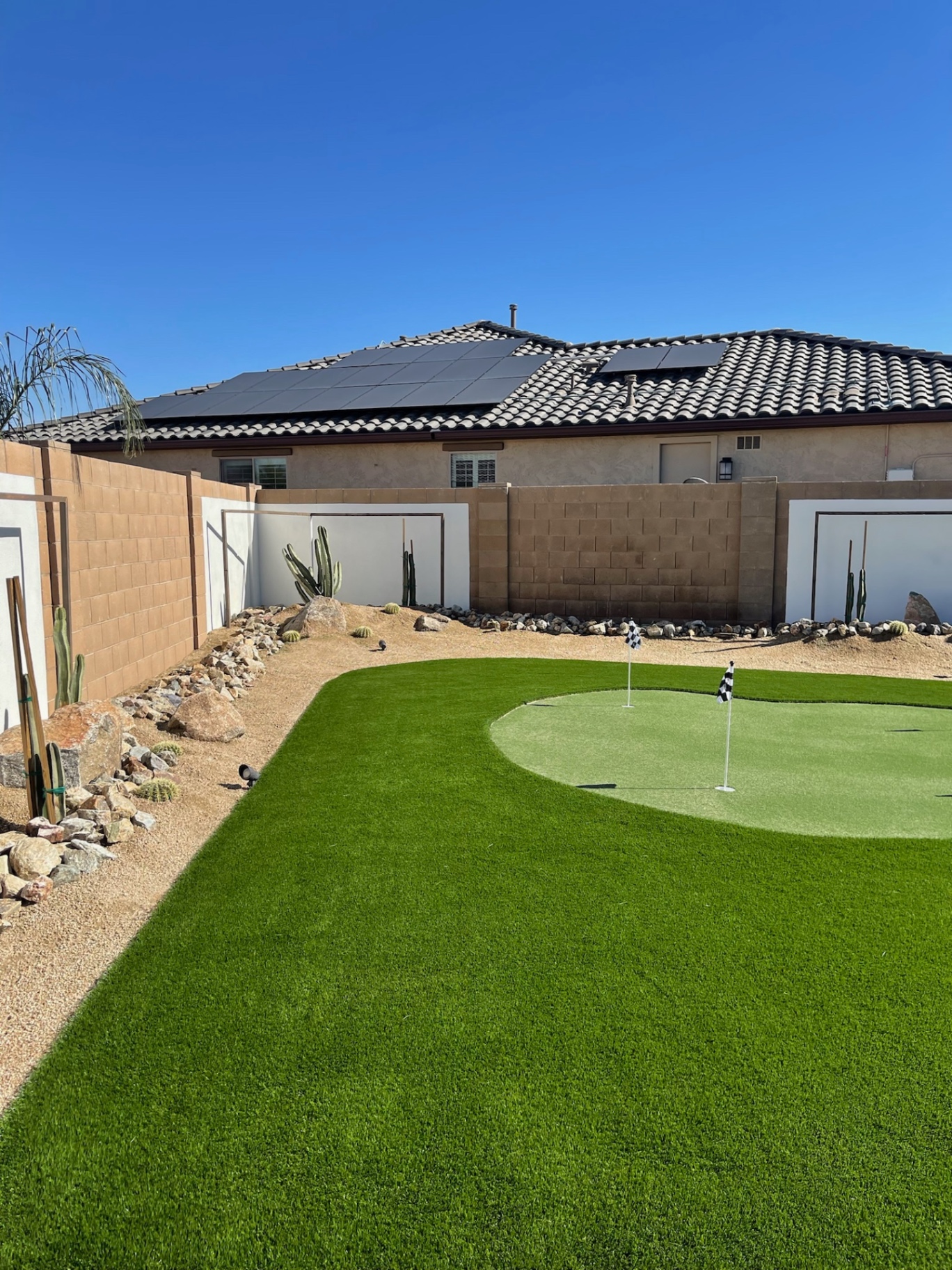 Goodyear artificial turf lawn and putting green with saguaro-and-boulder desert border by AE Outdoor Living