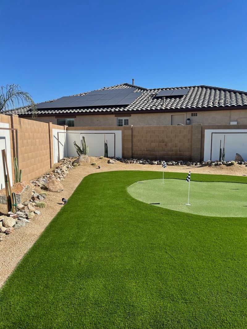 Goodyear artificial turf lawn and putting green with saguaro-and-boulder desert border by AE Outdoor Living