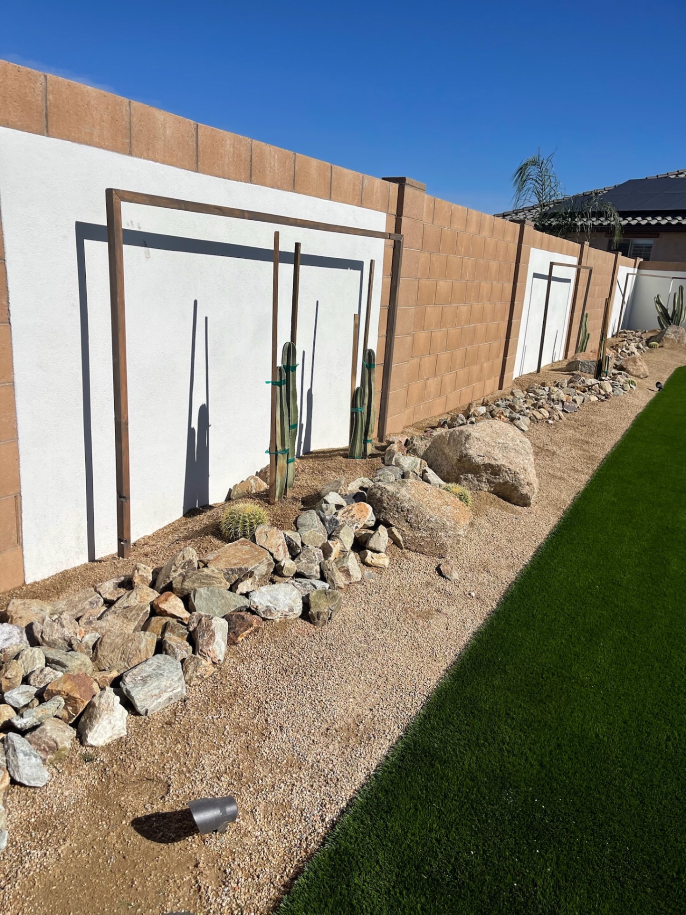 Goodyear side-yard desert-scape with rock border, boulders and cactus meeting fresh artificial turf lawn by AE Outdoor Living
