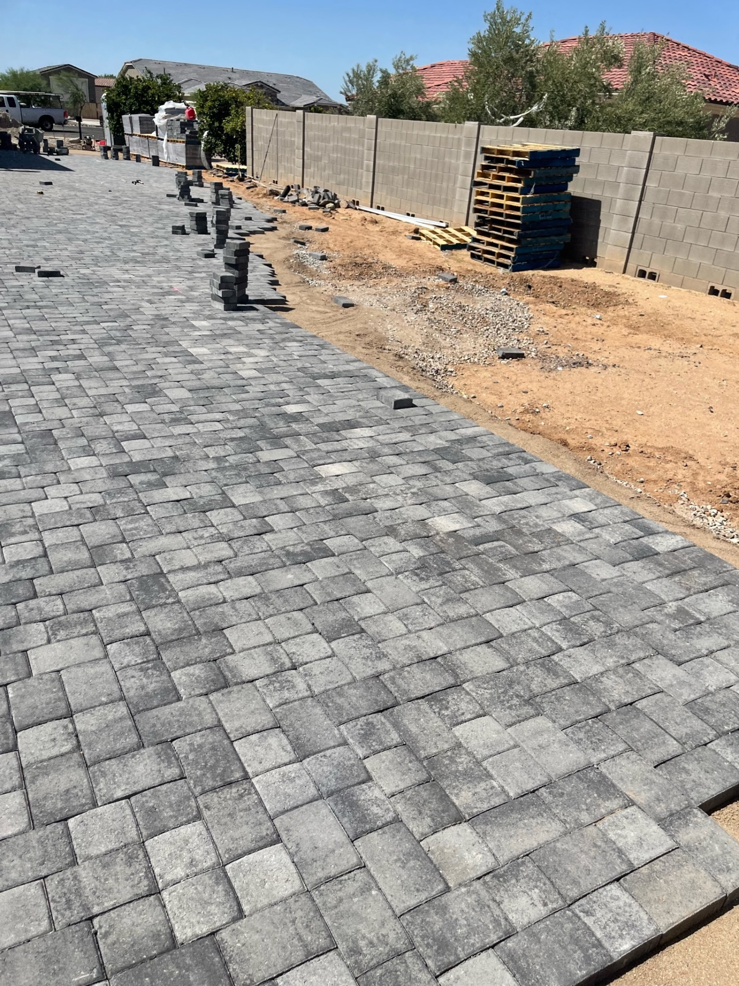 Waddell (Surprise-area) long side-yard charcoal paver run bordering the block wall with stacked edge pieces prepared for final soldier course by AE Outdoor Living