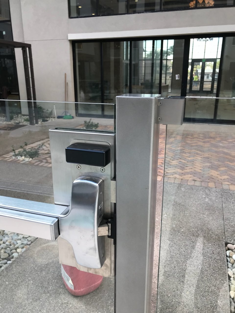 Detail of gate hardware fixed through a glass panel at a multifamily pool-area entrance.