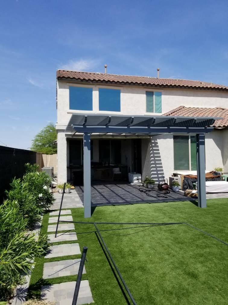 The Meadows (Peoria) house-attached grey alumawood pergola over tile-paver patio with artificial turf lawn, paver stepping stones and oleander privacy hedge by AE Outdoor Living