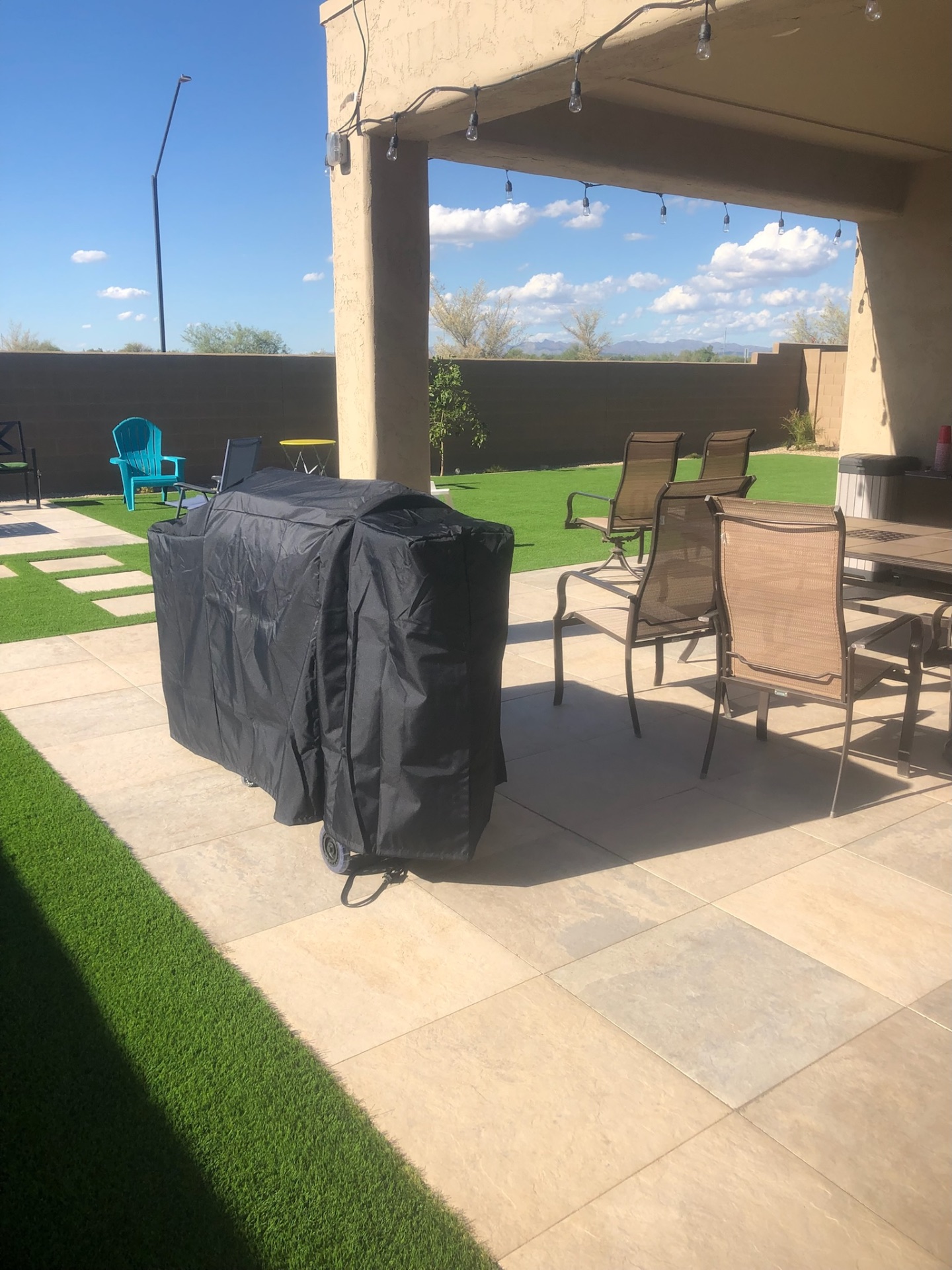 Buckeye covered outdoor living space with travertine paver flooring and string-light patio