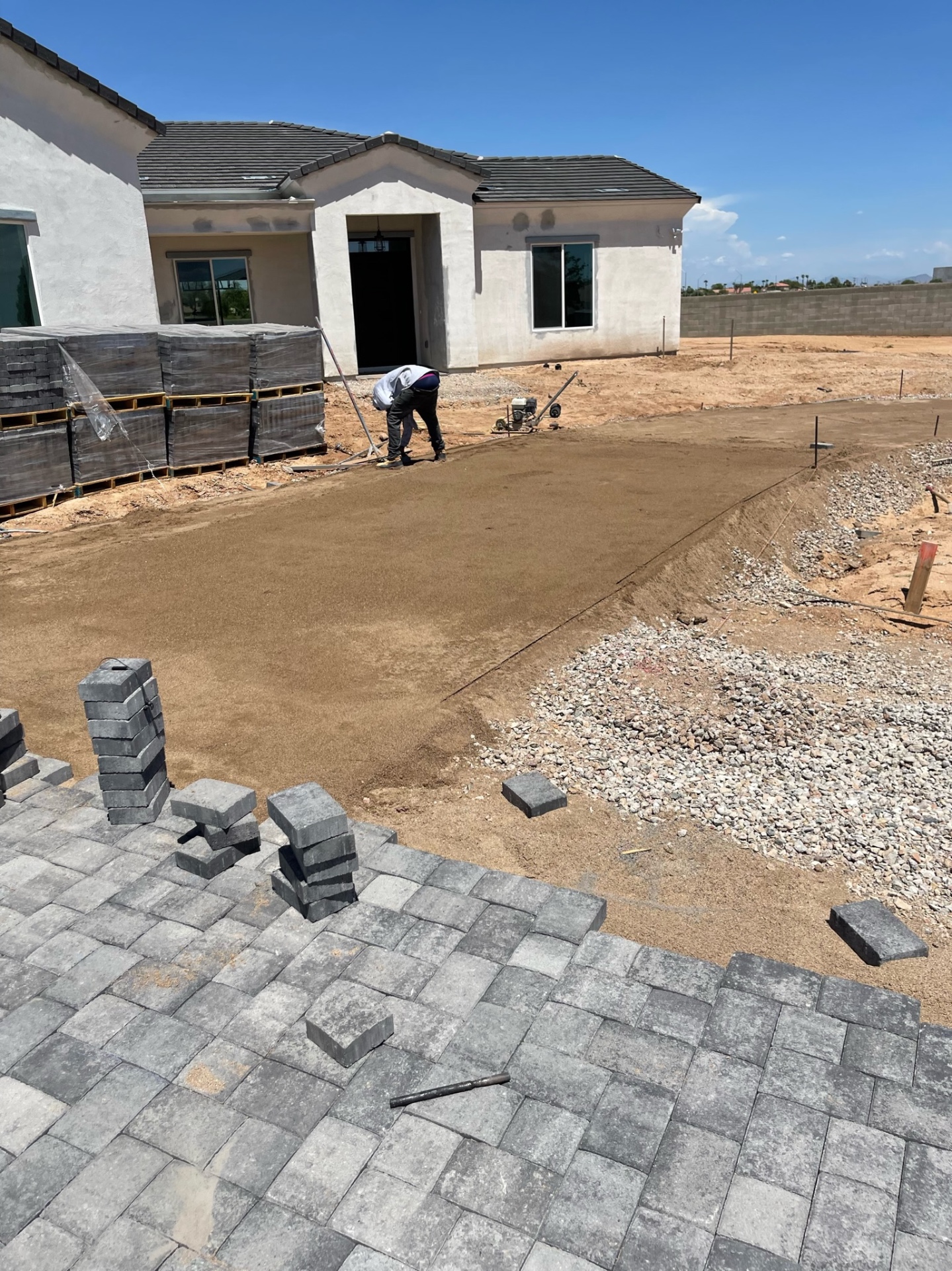 Waddell (Surprise-area) screeded sand bed with edge-restraint line ready for next paver course, adjoining laid charcoal paver field by AE Outdoor Living