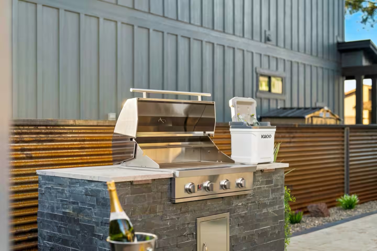 Built-in outdoor kitchen with BBQ island, stone veneer, counter, storage, and low-voltage lighting