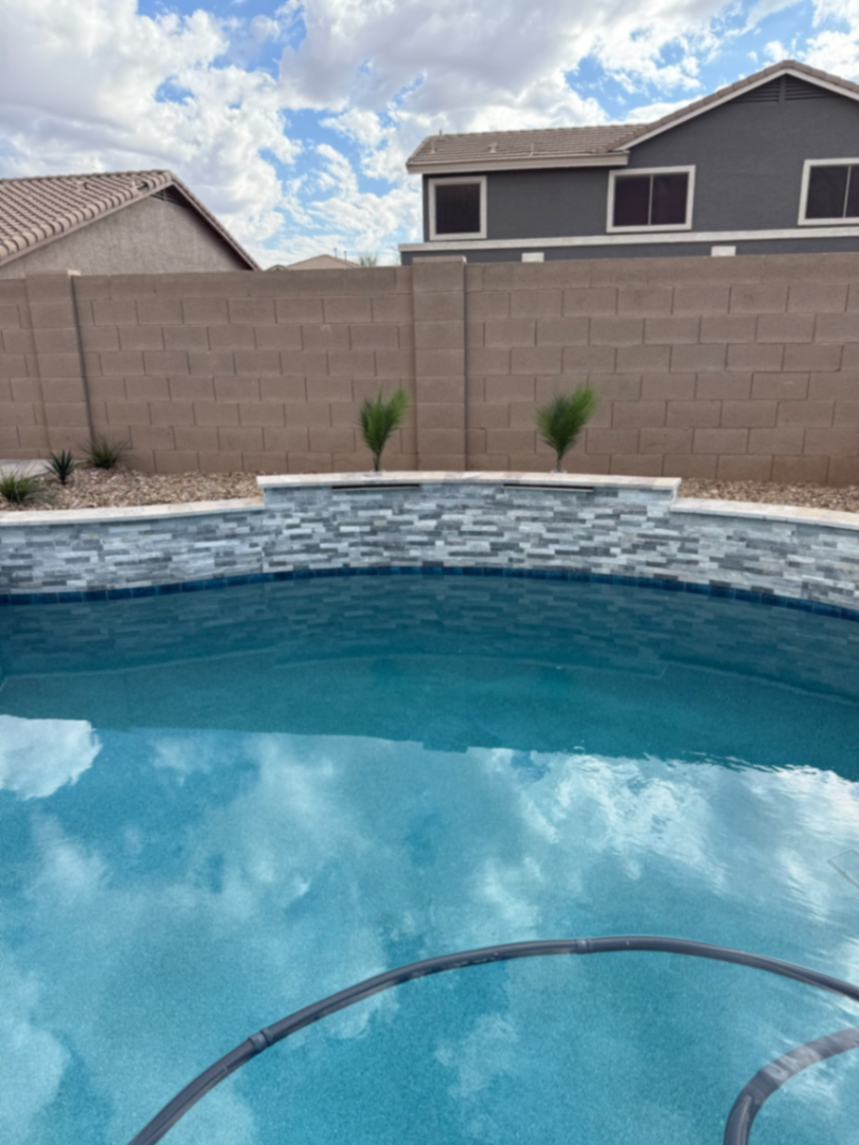 Thorn residence, Mesa AZ — close-up of stacked-stone spa wall, waterline tile band, and pebble finish.