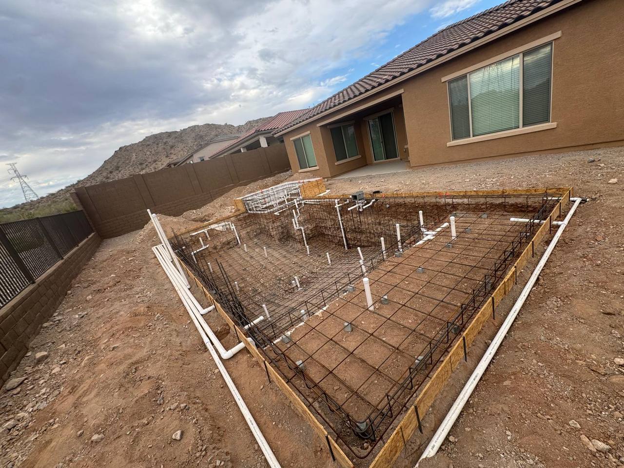 Engineered rebar cage and pool plumbing rough-in on a new build with mountain-view backdrop.