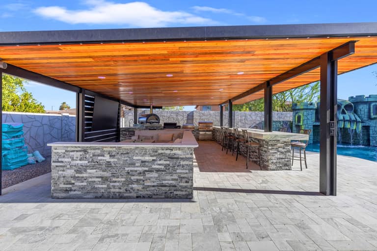 Front view into a covered Litchfield Park pavilion with fire seating, an outdoor kitchen and bar stools.